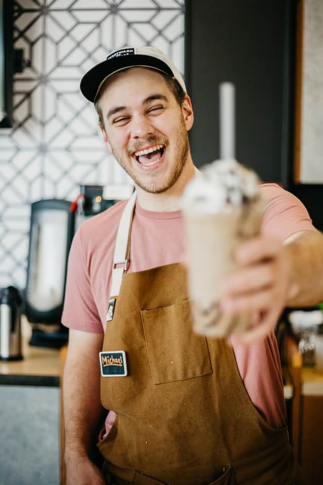 Smiling chef holding a healthy smoothie made from fresh seasonal fruits